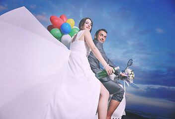 Image showing just married couple on the beach ride white scooter