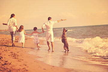 Image showing happy family playing with dog on beach