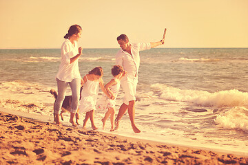 Image showing happy family playing with dog on beach