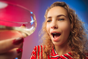 Image showing The surprised young woman in party clothes posing with glass of wine.