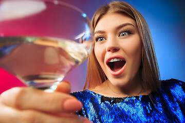 Image showing The surprised young woman in party clothes posing with glass of wine.