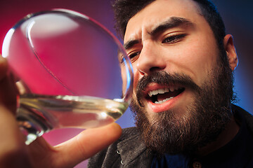 Image showing The surprised young man posing with glass of wine.