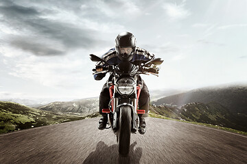 Image showing biker on mountain highway, riding around a curve with a motion blur toned with a retro vintage instagram filter app or action