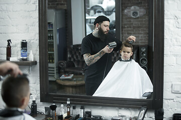 Image showing Children hairdresser cutting little boy against a dark background.