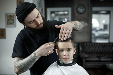 Image showing Children hairdresser cutting little boy against a dark background.