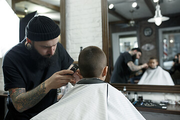 Image showing Children hairdresser cutting little boy against a dark background.