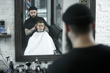 Image showing Children hairdresser cutting little boy against a dark background.