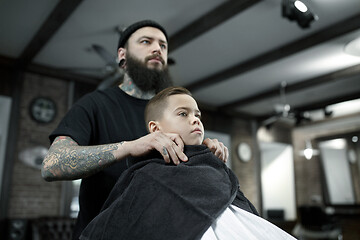 Image showing Children hairdresser cutting little boy against a dark background.