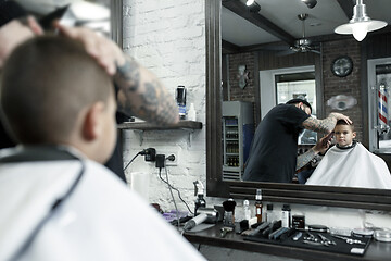 Image showing Children hairdresser cutting little boy against a dark background.