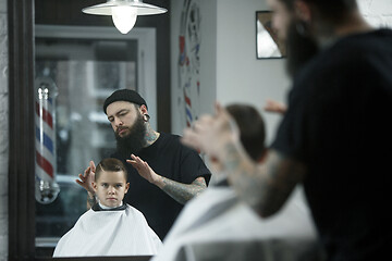 Image showing Children hairdresser cutting little boy against a dark background.