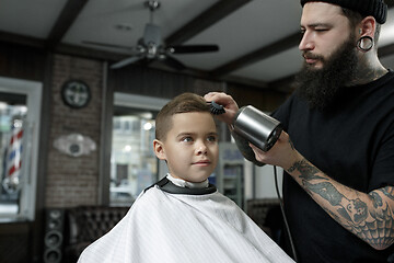 Image showing Children hairdresser cutting little boy against a dark background.