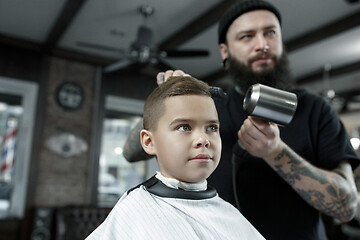 Image showing Children hairdresser cutting little boy against a dark background.