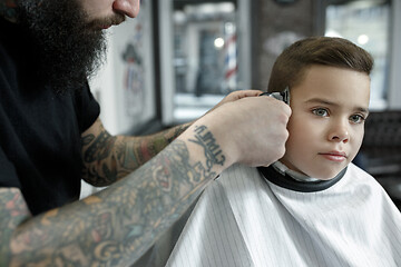 Image showing Children hairdresser cutting little boy against a dark background.