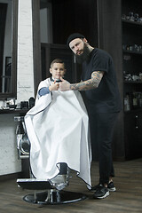 Image showing Children hairdresser cutting little boy against a dark background.