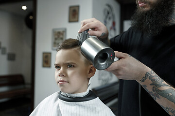 Image showing Children hairdresser cutting little boy against a dark background.