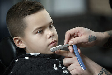 Image showing Children hairdresser cutting little boy against a dark background.