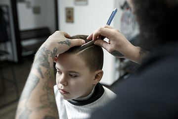 Image showing Children hairdresser cutting little boy against a dark background.