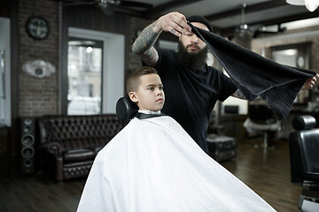 Image showing Children hairdresser cutting little boy against a dark background.