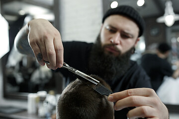 Image showing Children hairdresser cutting little boy against a dark background.