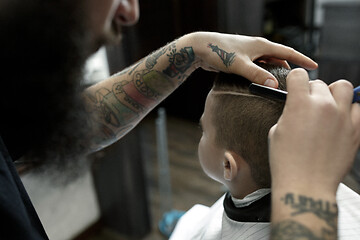 Image showing Children hairdresser cutting little boy against a dark background.