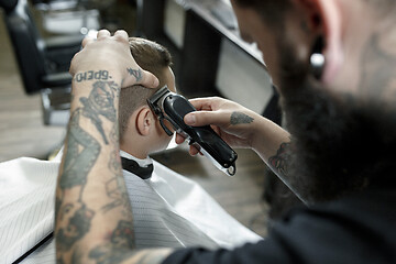 Image showing Children hairdresser cutting little boy against a dark background.