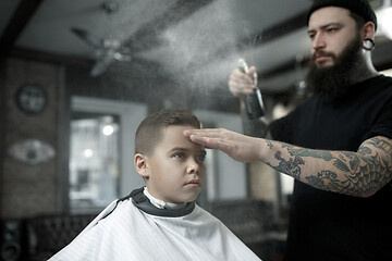 Image showing Children hairdresser cutting little boy against a dark background.