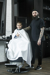 Image showing Children hairdresser cutting little boy against a dark background.