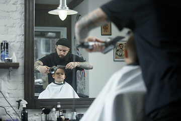 Image showing Children hairdresser cutting little boy against a dark background.