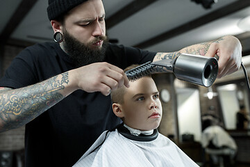 Image showing Children hairdresser cutting little boy against a dark background.