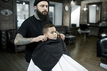 Image showing Children hairdresser cutting little boy against a dark background.