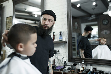 Image showing Children hairdresser cutting little boy against a dark background.