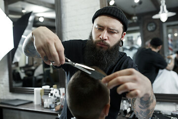 Image showing Children hairdresser cutting little boy against a dark background.