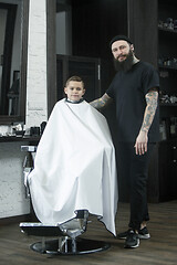 Image showing Children hairdresser cutting little boy against a dark background.