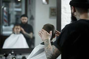 Image showing Children hairdresser cutting little boy against a dark background.