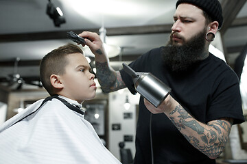 Image showing Children hairdresser cutting little boy against a dark background.