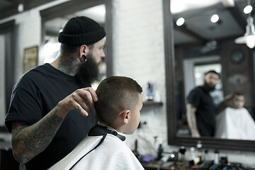 Image showing Children hairdresser cutting little boy against a dark background.