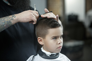 Image showing Children hairdresser cutting little boy against a dark background.