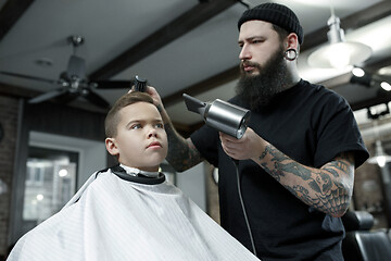 Image showing Children hairdresser cutting little boy against a dark background.