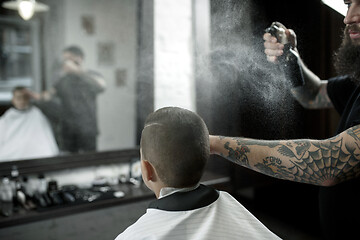 Image showing Children hairdresser cutting little boy against a dark background.