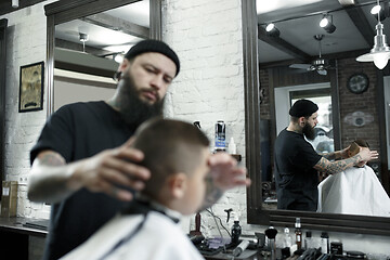 Image showing Children hairdresser cutting little boy against a dark background.