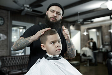 Image showing Children hairdresser cutting little boy against a dark background.