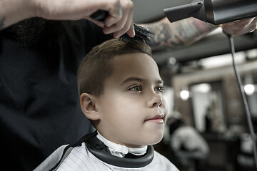 Image showing Children hairdresser cutting little boy against a dark background.