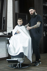 Image showing Children hairdresser cutting little boy against a dark background.