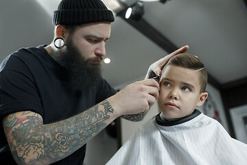 Image showing Children hairdresser cutting little boy against a dark background.