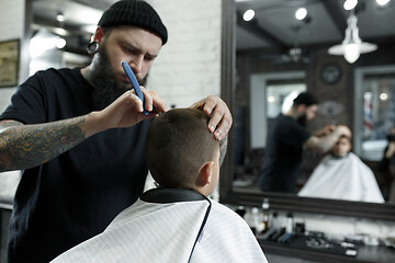 Image showing Children hairdresser cutting little boy against a dark background.