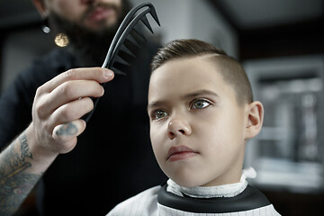 Image showing Children hairdresser cutting little boy against a dark background.