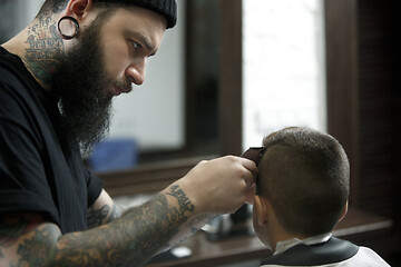 Image showing Children hairdresser cutting little boy against a dark background.