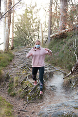 Image showing Corona virus, or Covid-19, is spreading all over the world. Portrait of caucasian sporty woman wearing a medical protection face mask while running in nature.