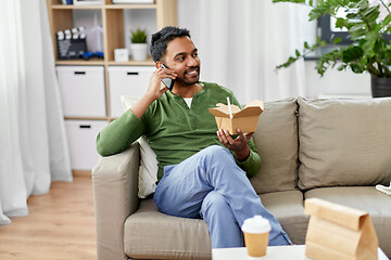 Image showing smiling indian man eating takeaway food at home