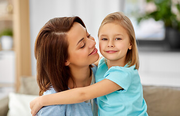 Image showing little daughter hugging her mother on sofa at home